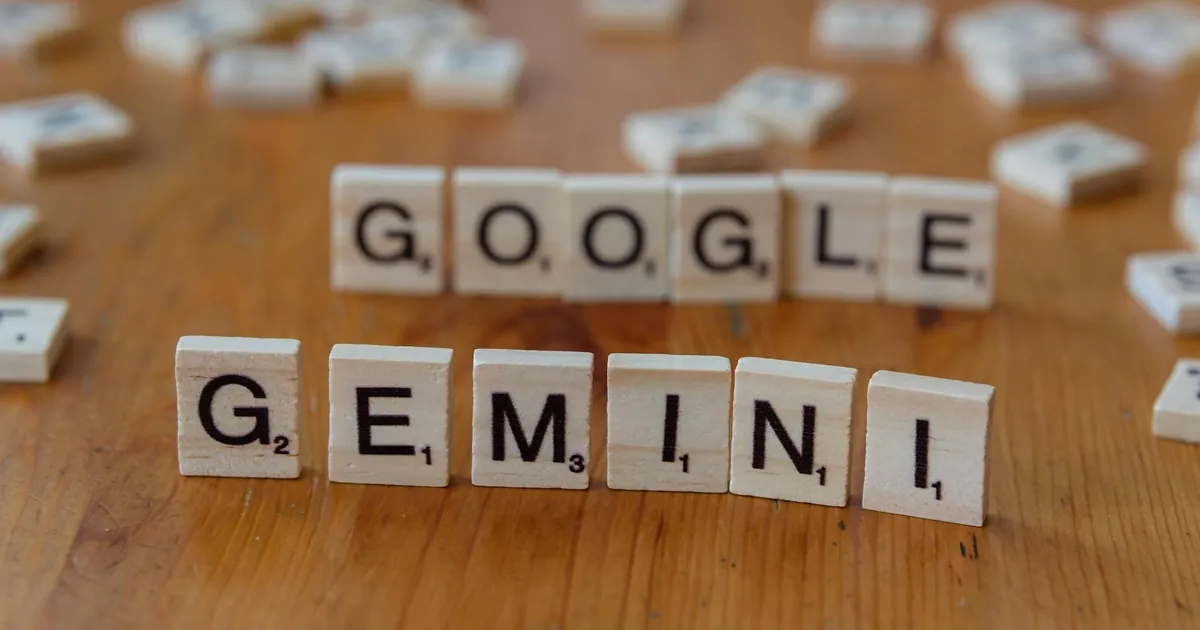 Scrabble tiles spelling out Google and Gemini on a wooden table, focusing on AI concepts.