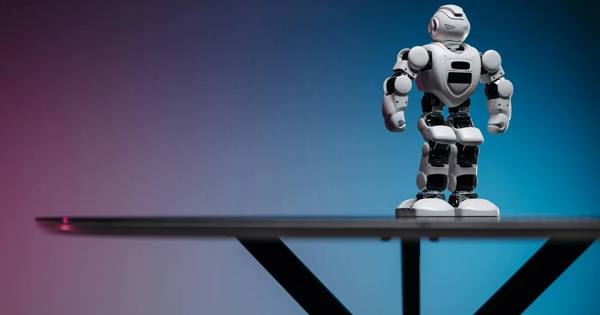 Close-up of a futuristic robot toy on a table with a gradient blue-pink background.