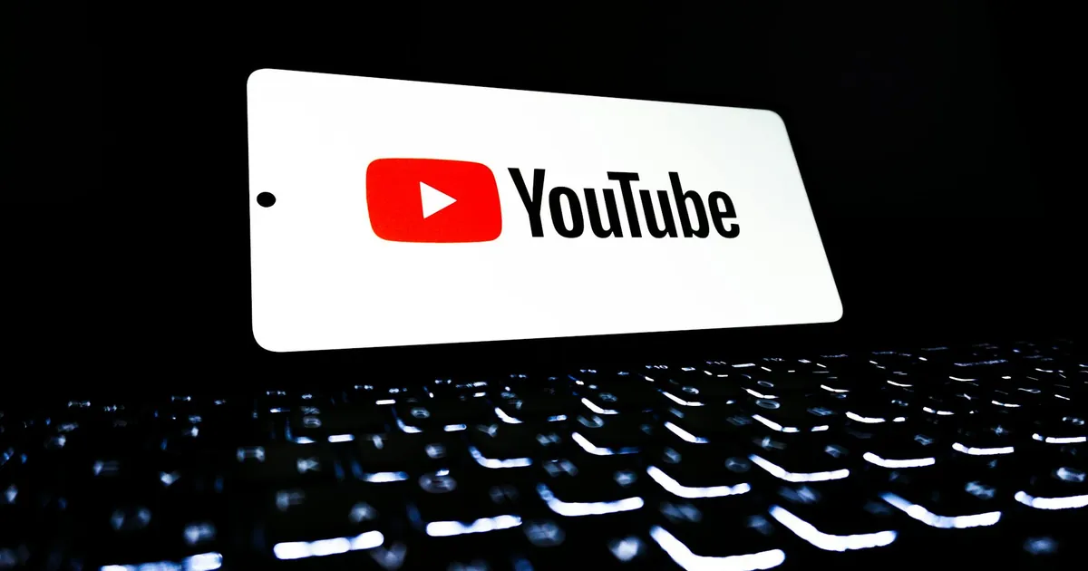 YouTube app icon displayed on a smartphone over an illuminated keyboard, representing digital media and online streaming.
