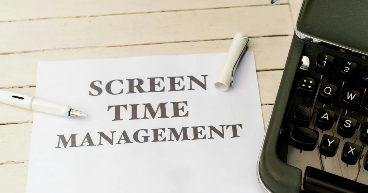 Typewriter with paper titled 'Screen Time Management' on a wooden table.