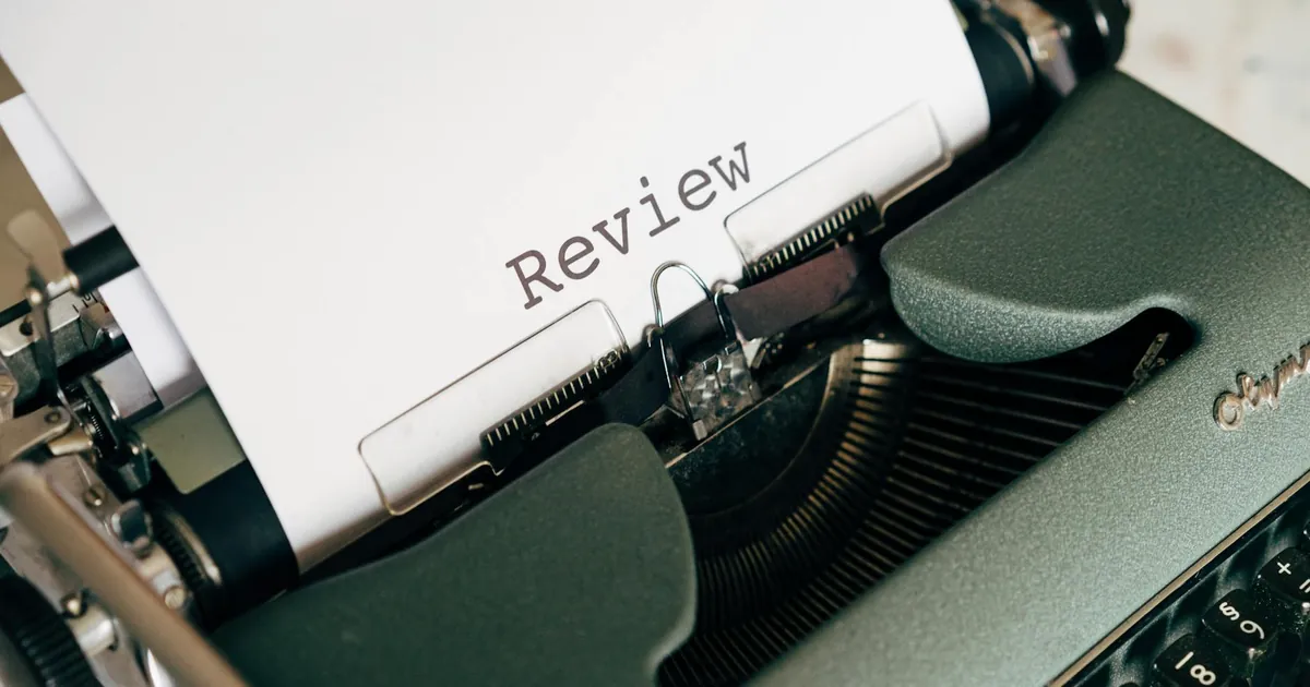 Close-up of an antique typewriter printing the word 'Review' on white paper.