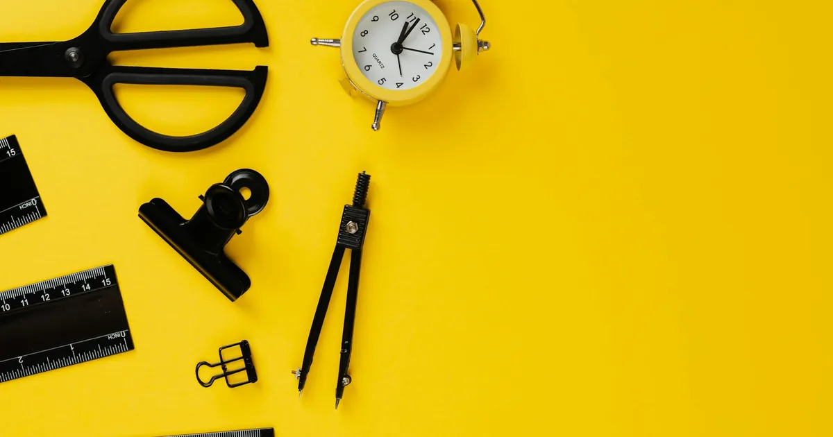 Desk essentials arranged on a vibrant yellow background, perfect for educational and organizational themes.